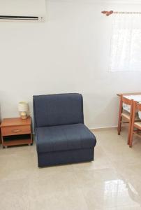 Apartment Sara في نجيفيش: كرسي أزرق في غرفة المعيشة مع طاولة