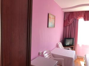 a room with a table and chairs and a tv at Avrora L in Zatoka
