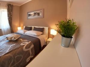 a bedroom with a bed and a potted plant on a table at Apartmani Violic in Punat