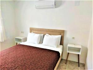 een slaapkamer met een bed met witte kussens en 2 tafels bij Gurkan Apart Hotel in Dalyan