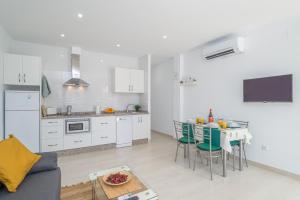 a kitchen with white cabinets and a table with chairs at Aire Siroco - Beach Apartment 13 in Benalmádena