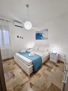 um quarto branco com uma cama e um cobertor azul em Albatros B&B Porto Cesareo em Porto Cesareo