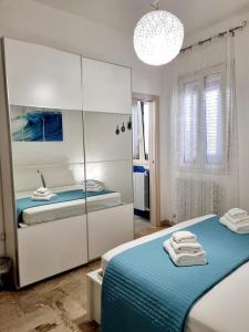 a white bedroom with two beds and a mirror at Albatros B&B Porto Cesareo in Porto Cesareo