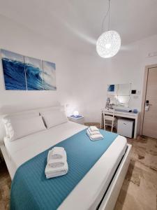 1 dormitorio con 1 cama blanca grande con manta azul en Albatros B&B Porto Cesareo, en Porto Cesareo