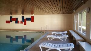 - une piscine avec 2 bancs à côté d'une piscine dans l'établissement Ferienwohnung FRIADO im Ferienpark Oberallgäu, à Missen-Wilhams