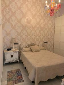 sypialnia z łóżkiem, stołem i żyrandolem w obiekcie APTO CALLE NUEVA 13 MALAGA Centro w Maladze