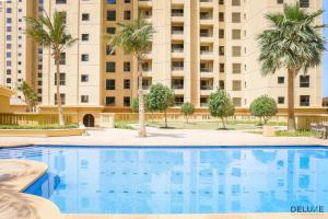 a swimming pool in front of a building with palm trees at Outstanding 3BR at Sadaf 7 JBR by Deluxe Holiday Homes in Dubai