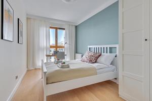 a white bedroom with a bed and a window at Apartament Baltic Bay Grudziądzka 4B Gdansk TriApart in Gdańsk