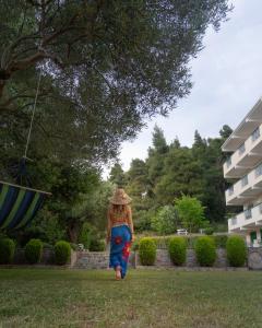 a woman in a hat walking through a park at Julia Hotel in Fourka