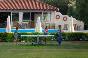 three girls standing in the grass in front of a pool at Julia Hotel in Fourka