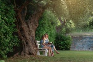 a woman sitting on a bench under a tree at Julia Hotel in Fourka