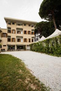 ein großes Gebäude mit Tischen und Sonnenschirmen davor in der Unterkunft Hotel La Tavernetta dei Ronchi in Marina di Massa