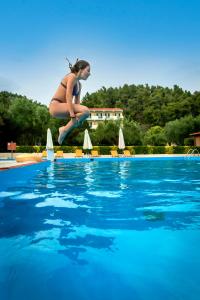 a woman in a bikini jumping into a swimming pool at Julia Hotel in Fourka