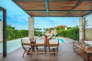 a patio with a table and chairs and a swimming pool at Sunny Villas Resort & Spa in Hanioti