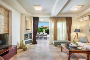 a living room with a couch and a tv at Sunny Villas Resort & Spa in Hanioti