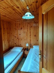two beds in a wooden room with a chandelier at Przy Latarni Morskiej in Jarosławiec