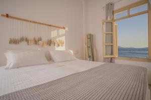 a bedroom with a large white bed and a window at Faro Sunset Suites in Mikonos