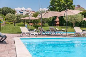 a swimming pool with lounge chairs and umbrellas next to a pool at Maj Premium Residence in Poreč
