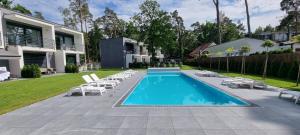 a swimming pool with lounge chairs and a house at Leo Royal Apartament Pobierowo in Pobierowo