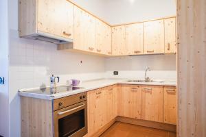 a kitchen with wooden cabinets and a sink at Residence Dolomia in Pozza di Fassa