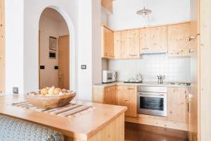 a kitchen with wooden cabinets and a bowl of fruit on a counter at Residence Dolomia in Pozza di Fassa