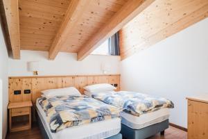 two beds in a room with wooden ceilings at Residence Dolomia in Pozza di Fassa