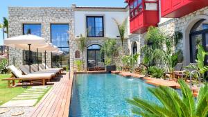 an outdoor swimming pool with chairs and an umbrella at Dmira Alacati in Alaçatı