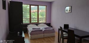 ein Schlafzimmer mit einem Bett und einem Tisch und einem Fenster in der Unterkunft Predela 1 - Studio 10 near Bansko Ski Lift in Bansko