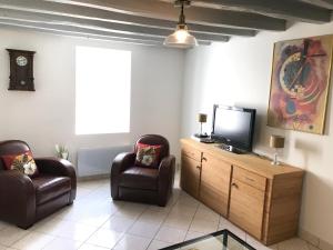 a living room with two chairs and a flat screen tv at La Loge de Gabrielle in Montlouis-sur-Loire