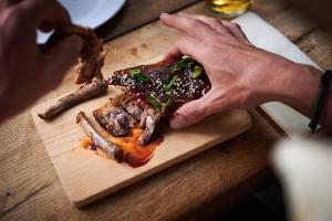 a person holding a piece of meat on a cutting board at Vert Lodge Chamonix in Chamonix-Mont-Blanc