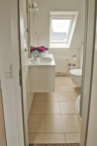 a bathroom with a sink and a toilet and a window at Apartmenthaus Hohenfels in Helgoland