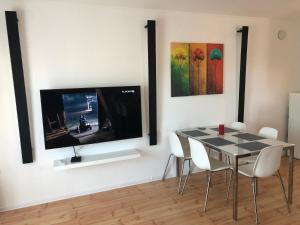 a dining room with a table and a tv on a wall at Hanga Apartman in Tiszafüred