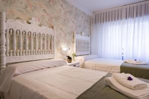 a white bedroom with two beds and a window at Pensión Ferradura in Melide +88 photos