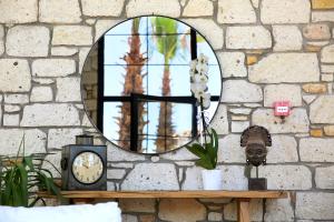 a mirror on a stone wall with a clock and flowers at Dmira Alacati in Alaçatı