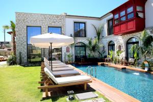 a pool with lounge chairs and an umbrella next to a house at Dmira Alacati in Alaçatı