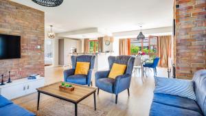 a living room with blue chairs and a brick wall at Domy nad Jeziorem Sun & Snow Osada Zamkowa in Pasym