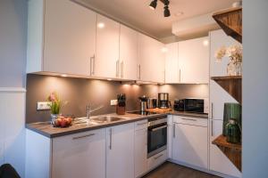 a kitchen with white cabinets and a sink at Ferienwohnung Strandhoch in Damp