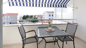 a table and chairs on a balcony with a window at Apartment Vegas in Novalja