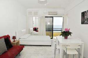 a white living room with a white bed and a table at Stadem Studios in Larnaca