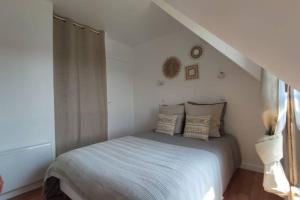 um quarto branco com uma cama com almofadas em La Pampa, Jardin aperçu mer - 4p em Houlgate