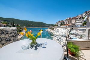 een witte tafel met gele bloemen op een balkon bij Apartmani Divna in Neum