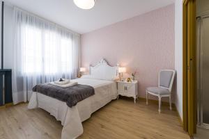 a bedroom with a white bed and a chair at Pensión Ferradura in Melide