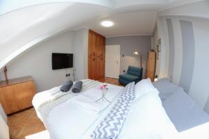 a bedroom with a large white bed and a blue chair at Apartment DobraYa Blue in Novi Sad