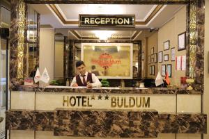 un hombre está parado detrás de un mostrador de hotel en Buldum Otel en Ankara
