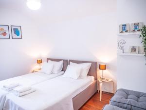 1 dormitorio con 2 camas con sábanas blancas y sofá en Pinna Apartments Hvar en Hvar