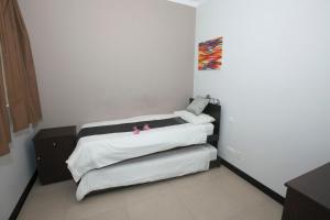 1 dormitorio con 1 cama con sábanas blancas y flores rosas en Best Of Xlendi SeaFront Apartments, en Xlendi