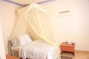 1 dormitorio con cama con dosel y mesa en The 4 JS Bed and Breakfast Emali, en Emali