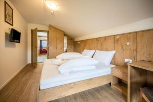 um quarto com uma cama com lençóis brancos e almofadas em Residence Condor Apt Schlern em Maranza