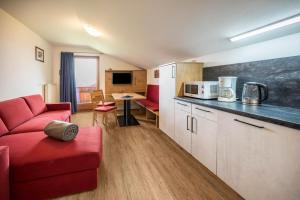 uma sala de estar com um sofá vermelho e uma cozinha em Residence Condor Apt Schlern em Maranza