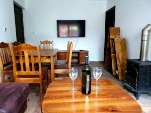 a bottle of wine sitting on a wooden table with two glasses at Penzión na Hálni in Nižná Boca